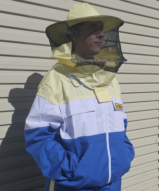 Happy Bee Australia model demonstrating the new sports style of protective beekeeping jackets. Giving 90s tracksuit vibes while standing in the sun in front of the garage door.