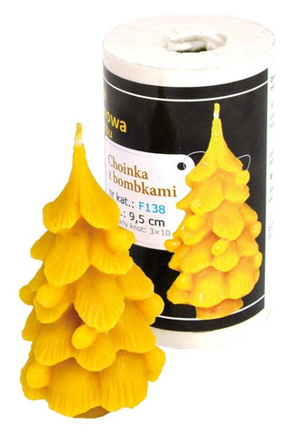 A silicone mould in the shape of a Christmas tree with yellow branches, alongside a few candles that have been made using the mould.