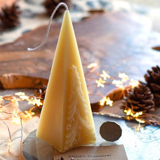 A beeswax candle shaped like a Christmas tree, placed on a plate with a card reading 'Lillian's Treasures'.