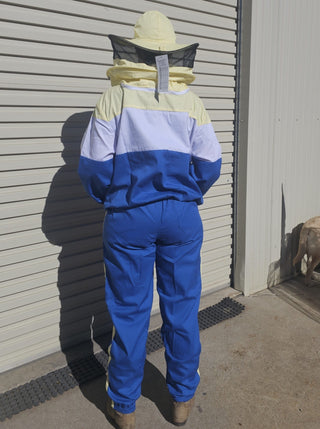 Person wearing a blue and yellow beekeeping suit standing in front of a closed garage door.