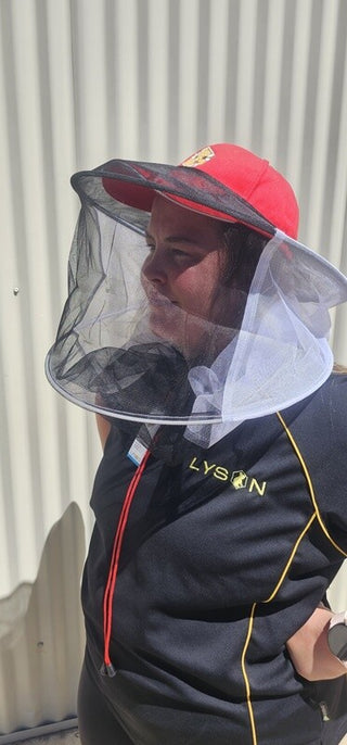 Our model is demonstrating how the universal black mesh veil attachment fits to any hat, in this case, a red baseball hat to offer protection from bees.